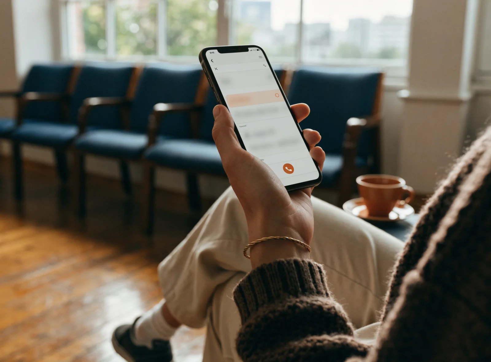 A phone in a clinic waiting room showing the practice's ad at the top of a doctor-name search